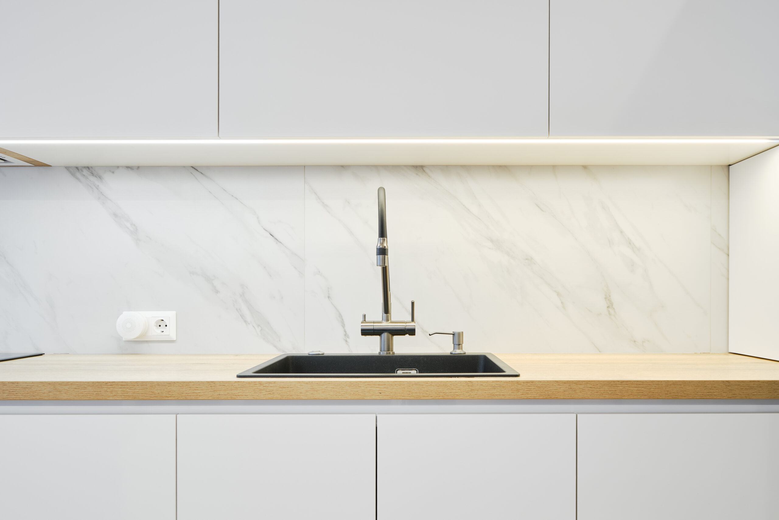 Modern kitchen backsplash with water tap and sink.